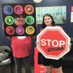 A woman with a "stop stigma" sign stands smiling
